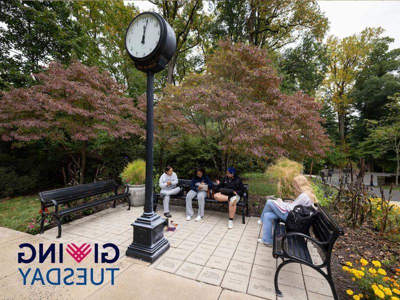 Students sitting on benches around a vintage clock